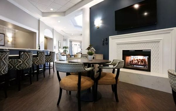 Resident bistro and dining tables in front of a fireplace in Seasons and Courtyard at Seasons