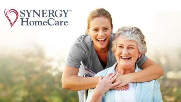 Female Synergy HomeCare of Tucson caregivver hugging senior woman in chair