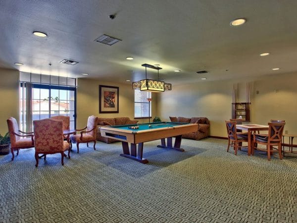 Game room in The Woodmark at Sun City with a green felt billiards table and seating areas