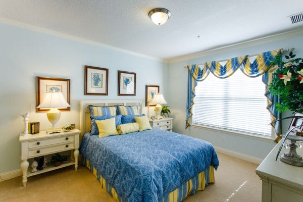 Model bedroom with blue bedspread in The Brennity at Tradition
