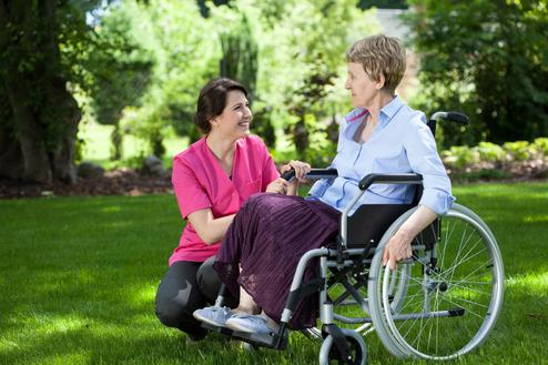 Woman in wheelchair talking with female Assisted Care Services caregiver