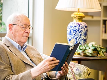 Senior male resident of Finlay House reading a book