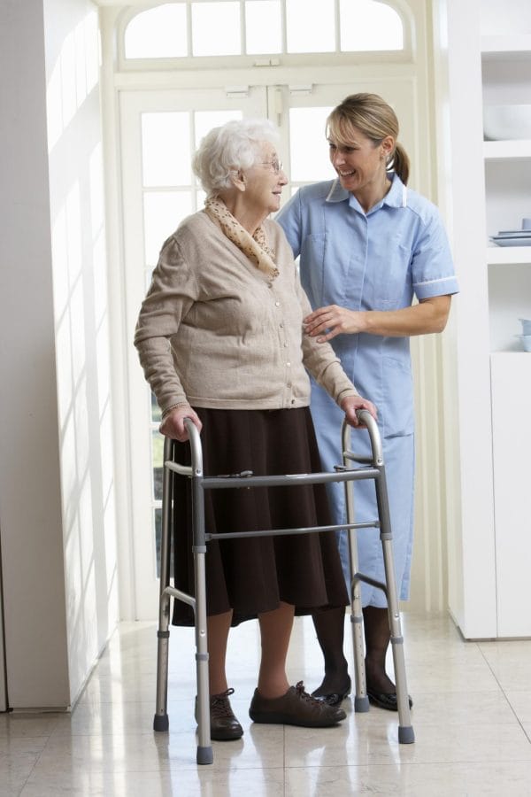 Caregivers That Deliver employee helping senior woman in walker