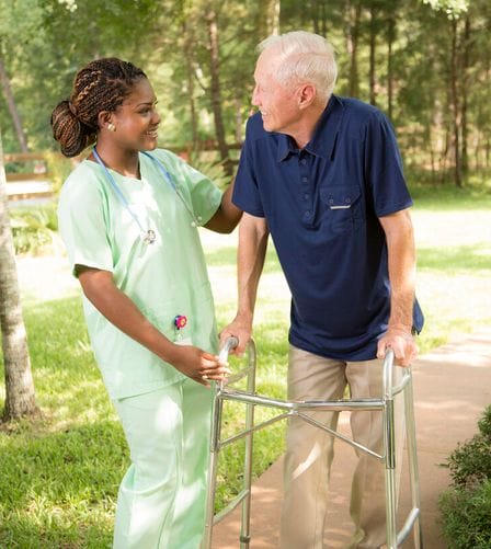 Senior man in walker being assisted by a female AAA T.L.C. Health Caregiver