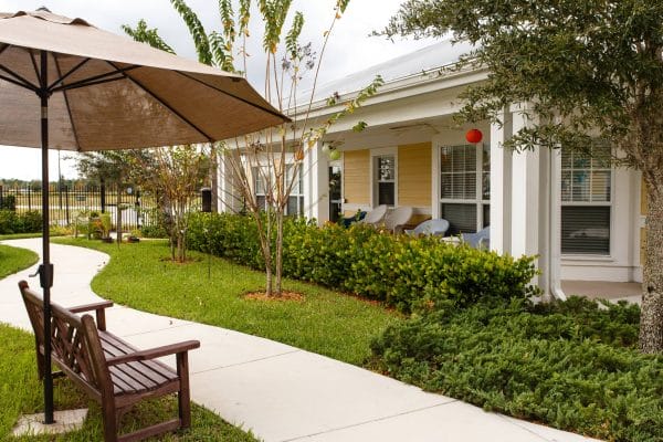 Outdoor walking path with park bench and umbrella in The Brennity at Tradition courtyard
