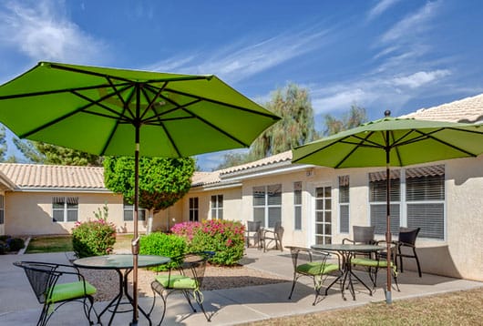 Kingswood Place Assisted Living Community patio filled with green umbrella tables