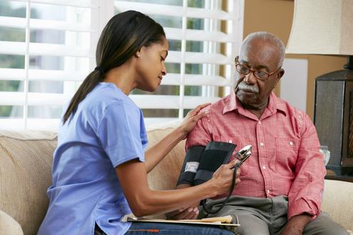 Female Assisted Care Services caregiver checking blood pressure of senior man with mustache