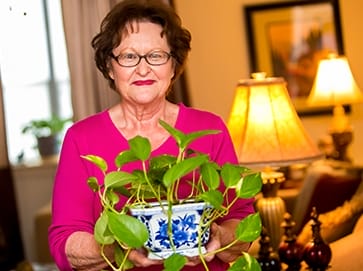 Female resident of Finlay House holding a plant
