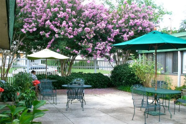 Resident courtyard with umbrella tables outside of Magnolia Manor of Greenville