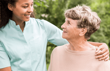 Senior woman smiling at female Kindred at Home caregiver