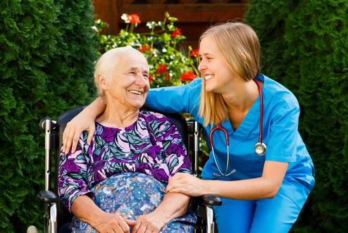 Senior woman smiling and embracing with female Assisted Care Services caregiver