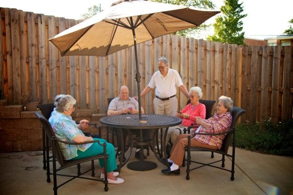 Regency Retirement Village - Tuscaloosa restidents sitting at a outdoor table covered by an umbrella