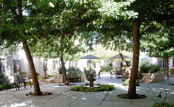 The Inn at Freedom Plaza outdoor courtyard filled with shade trees and umbrella tables
