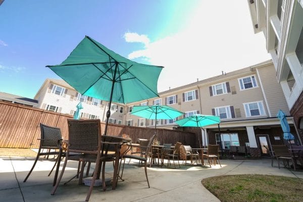 Umbrella covered tables on the Covered driveway entrance to Harmony at Five Forks outdoor patio