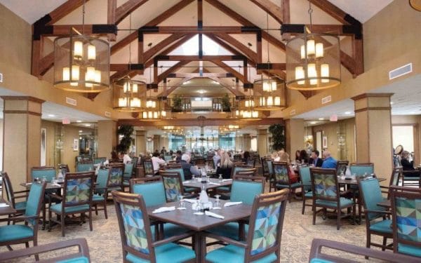 Dining hall with vaulted exposed beam ceilings and resident dining tables at Arrowhead Valley Retirement Resort