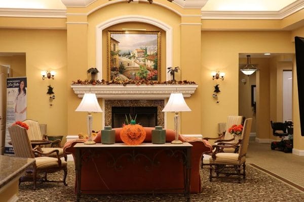 Main gathering area at Aston Gardens at Pelican Pointe with couches, fireplace and fall decorations