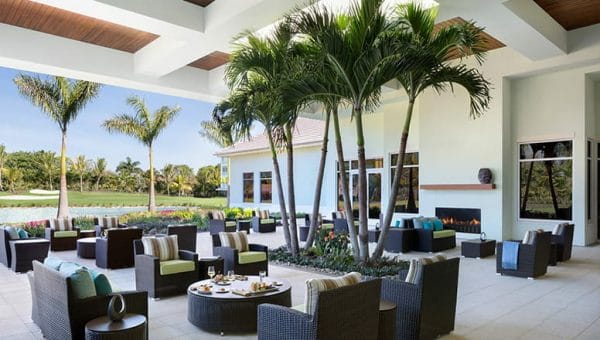 Outdoor seating under palm trees on the Vi at Bentley Village terrace
