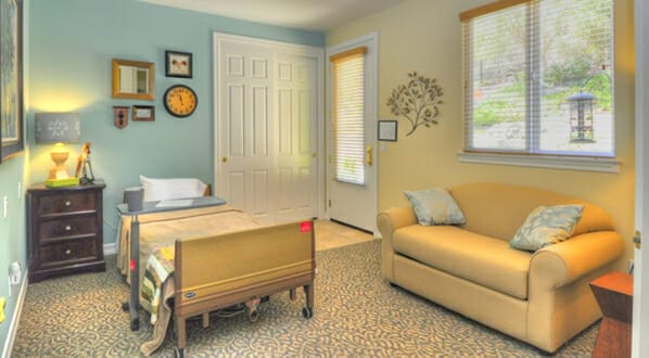 Bedroom at Hospice of North Coast. Includes a tan loveseat with a door to the exterior. Also includes dresser.
