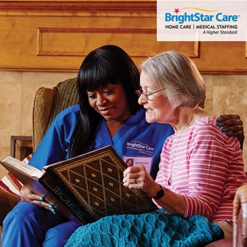 BrightStar Care Of Columbia caregiver looking at photo album with senior woman
