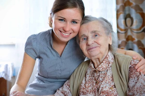 Female Americare Plus caregiver embracing senior woman