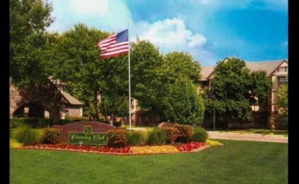 Front entrance area with flowers and hedges and American flag at Country Club At Woodland Hills