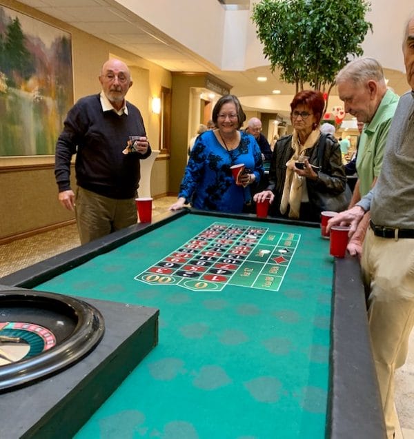 Residents of Daniel Pointe Retirement playing gambling games on roulette wheel table