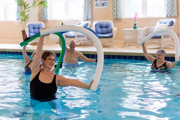 Seniors at Franke at Seaside using noodles in the indoor pool during an exercise class
