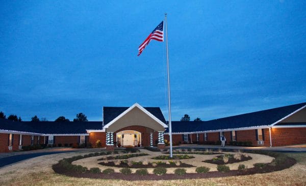 Front of building with American flag pole at Commonwealth Senior Living at Chesterfield at twilight