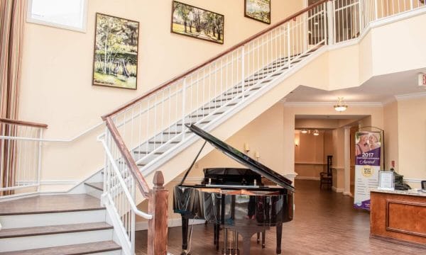 Grand staircase and piano in the lobby of HarborChase of Tallahasee
