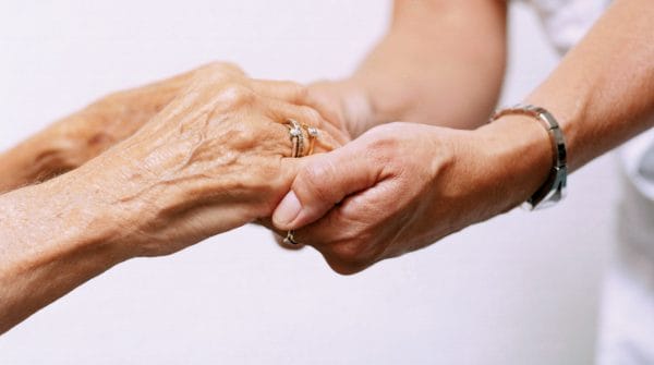 Elderly womans hands holding womans hands
