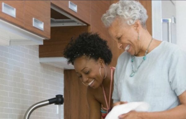 Senior Woman Smiling at Young Lady at the Sink