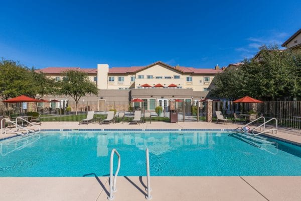 Mountain Park Senior Living outdoor swimming pool with lounge chairs and umbrella tables