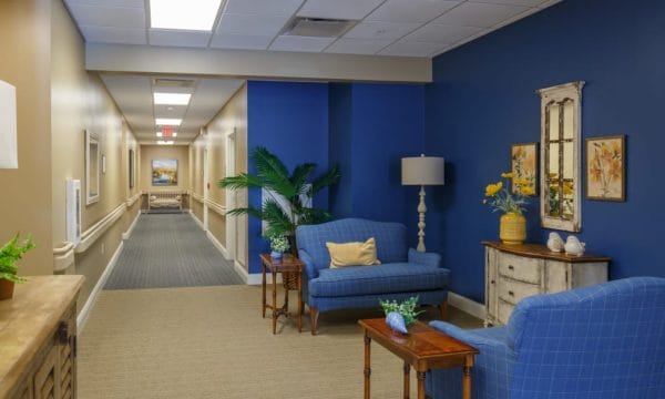 Sitting area with blue walls and loveseats with resident hallways in the background at Keystone Place at Terra Bella