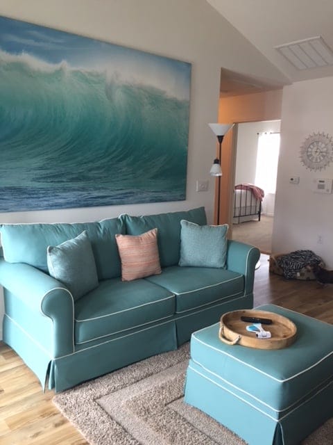 Big comfy aqua colored sofa with painting behind in residence at Crossings at Heritage