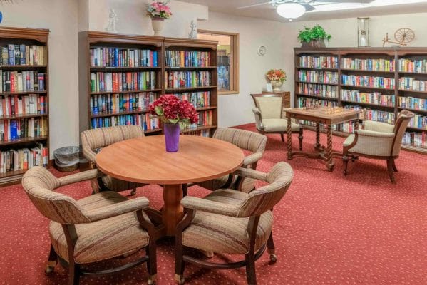 Library stocked with books, dvds and sitting area including two tables and chairs at Hilltop Estates