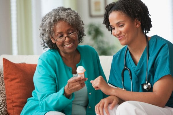 Senior woman managing medication with help from a Americare Plus cargiver