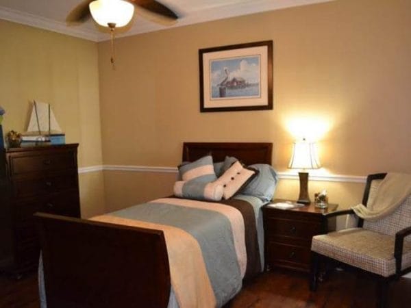 Resident bedroom with chair rail and ceiling fan at Pacifica Senior Living Fort Myers