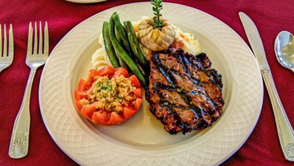 Gourmet steak dinner with green beans and beefsteak tomato from the kitchen of The Forum at Desert Harbor
