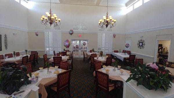 Savannah Grand of Amelia Island dining room with large chandeliers and many tables for residents