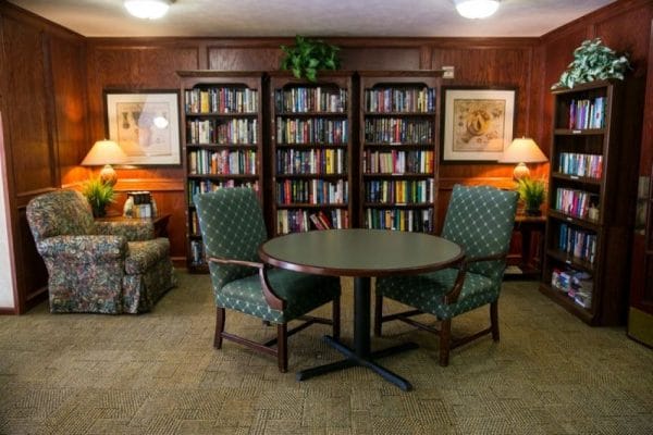 Dark wood walls of Savannah Pines Retirement library with built in book cases and seating for residents