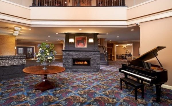 The Bristal Assisted Living at Armonk lobby with a grand piano, cozy fireplace and open ceiling to second floor