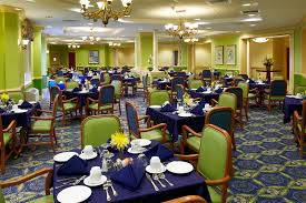 The Bristal Assisted Living at East Northport dining room with green upholstered chairs and navy blue tableclothes
