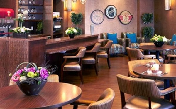 Lounge and bar area with wood floors and cocktail tables at The Bristal Assisted Living at East Northport
