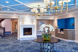 Lobby area with reception desk and white fireplace at The Bristal Assisted Living at Jericho