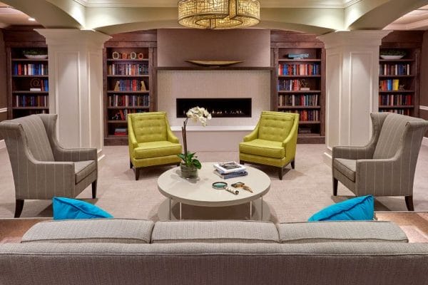 The Bristal Assisted Living at Jericho resident lounge with a fireplace flanked by two bookcases and comfortable seating