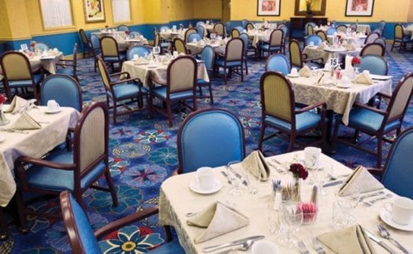Inviting dining room with yellows and blues at The Bristal Assisted Living at Lynbrook