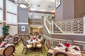 The Bristal Assisted Living at North Hills dining room with ornate staircase on the right goooing up to second level