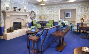 The Bristal Assisted Living at Sayville community living room with colorful blue rug and sofa in front of a white fireplace