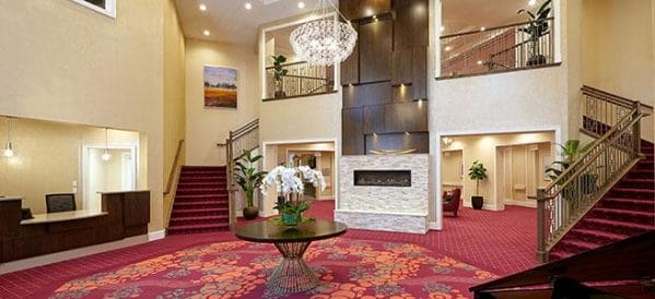 Lobby of The Bristal Assisted Living at Wayne with curved staircase and two story fireplace and red carpet