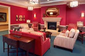 Community living room at The Bristal Assisted Living at Woodcliff Lake with rich red walls and a large fireplace